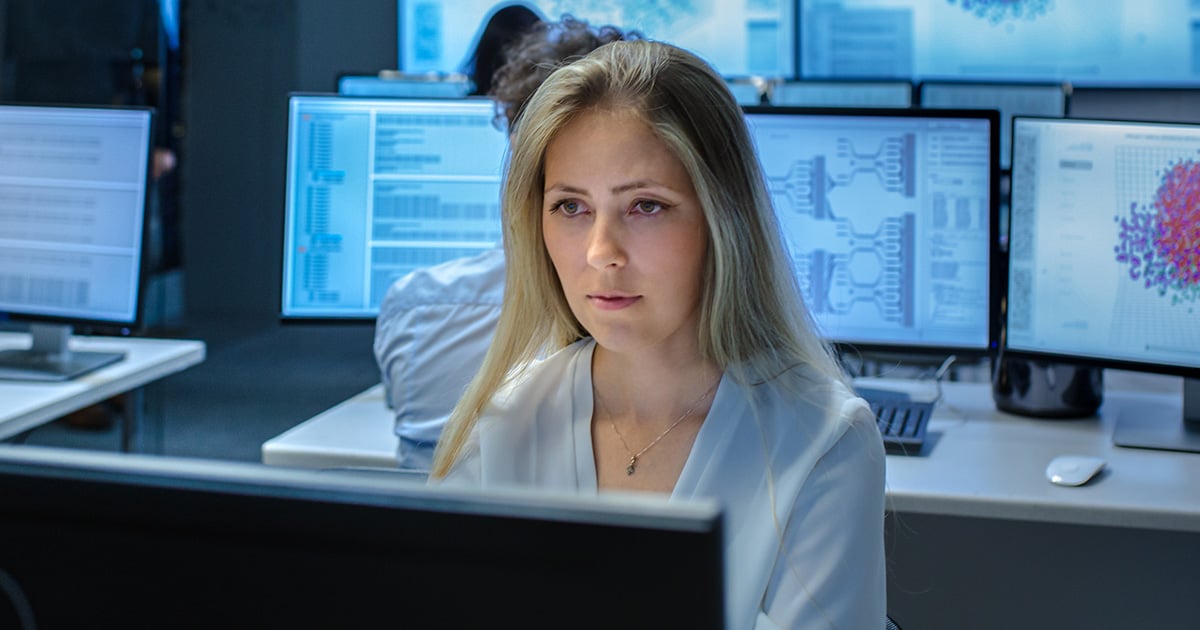 Female Computer Engineer Works on a Neural Network/ Artificial Intelligence Project with Her Multi-Ethnic Team of Specialist. Office Has Multiple Screens Showing 3D Visualiation.