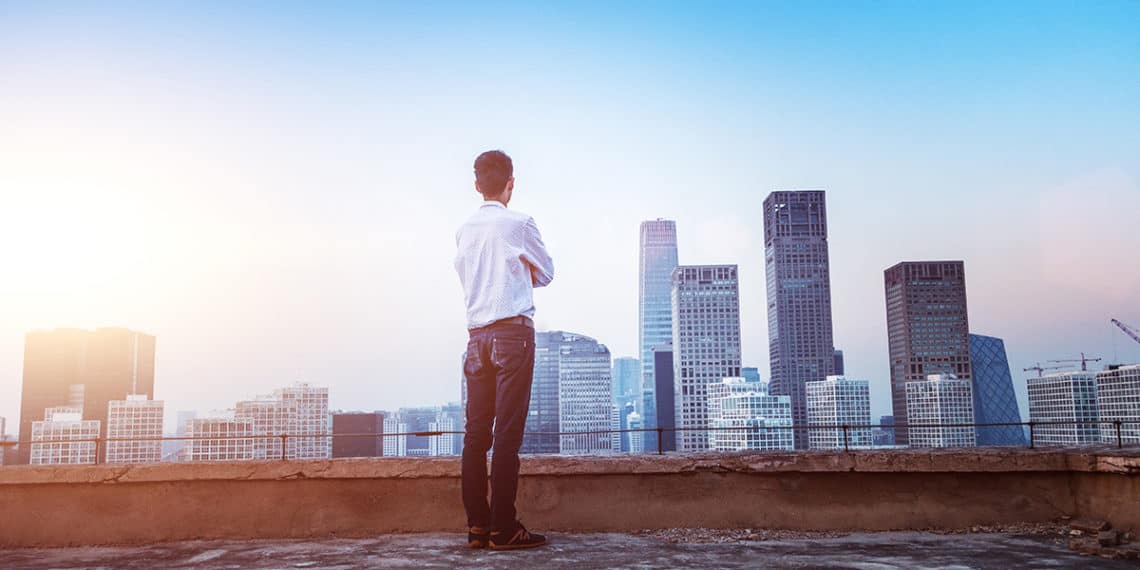Businessman Looking At Cityscape With Sunlight