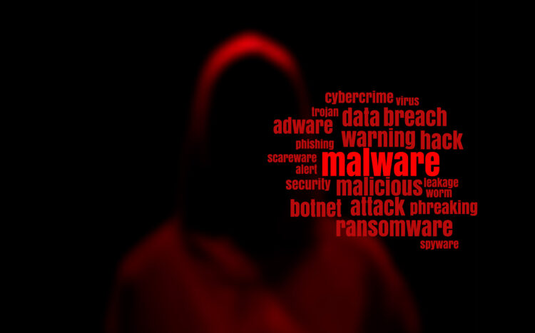 Dark red silhouette of a hacker in a hoodie with malware tag cloud